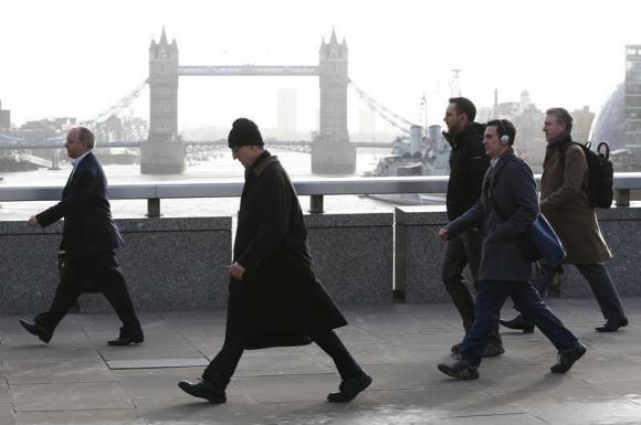 Tower Bridge is seen behind commuters as they walk across London Bridge during an Underground strike in London